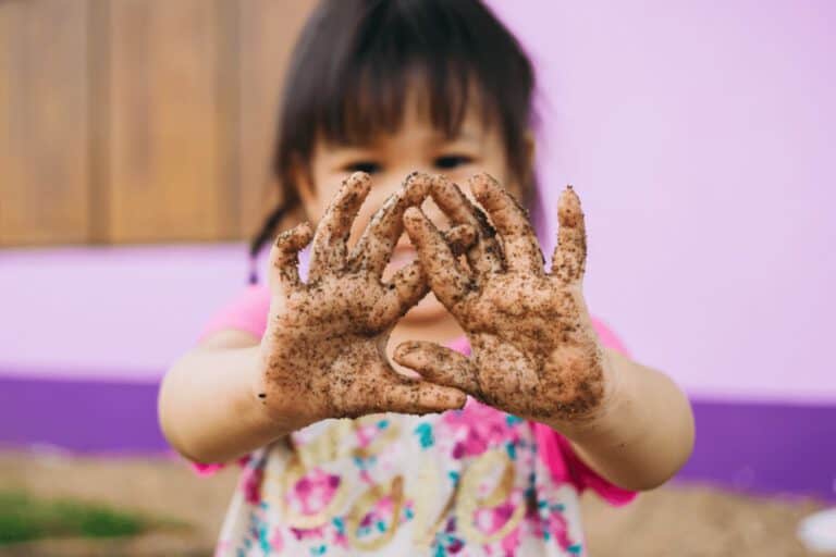 ילדה המציגה את כפות ידיה המלאות בבוץ