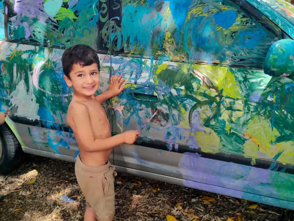 ילד מצייר על רכב כחלק מטיפול באומנות.