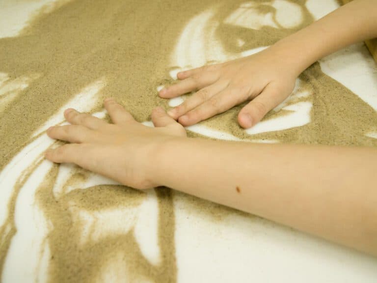 ילד משחק עם חול, מרגיש את המגע שלו. באינדקידס ניתן למצוא מרפאים בעיסוק