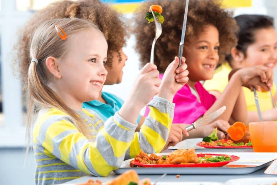 ילדים יושבים יחד לאכול ארוחת צהריים בעידן השפע