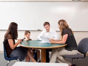 הורים יושבים עם ילד ומורה סביב שולחן